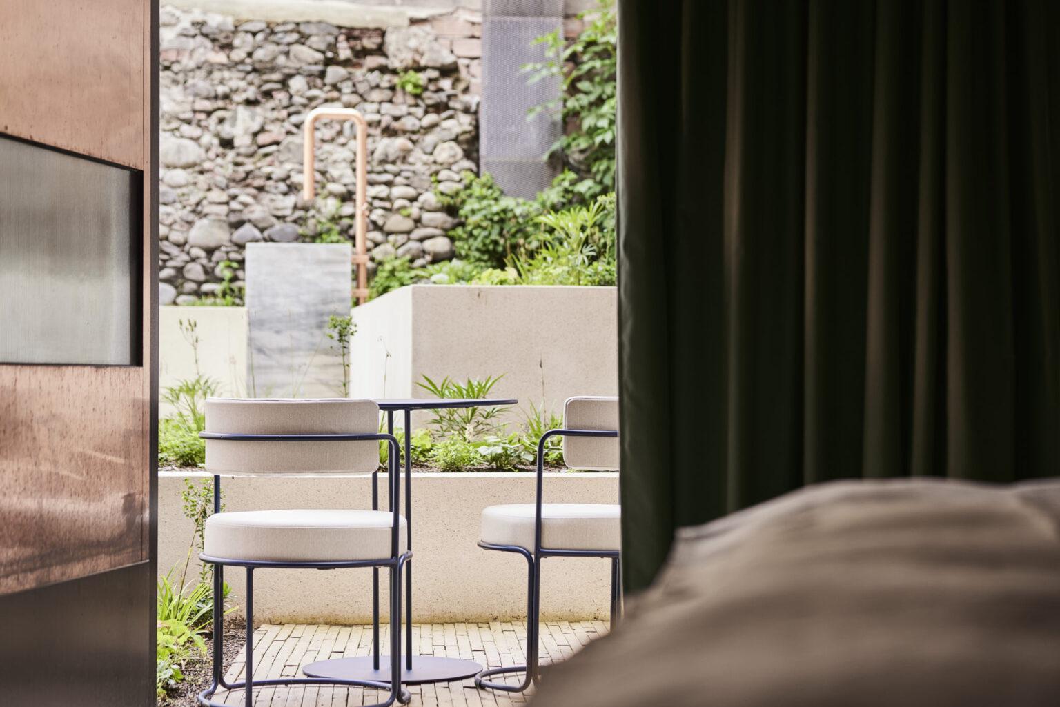 Parterre-Zimmer im Boutique Hotel Badhaus mit italienischem Leinen, Holzboden und Zugang zur Terrasse. Blick in Richtung Terrasse.